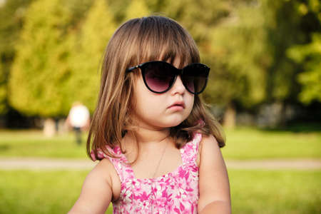 Little girl wearing mom's sunglasses. Portrait of a sweet baby girl who's stolen mom's sunglasses and happy to wear them trying to look like a grown up.の写真素材