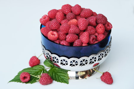 Fresh organic raspberries in a Vintage Glass Bowl with Metal Stand on white background. Red fresh...