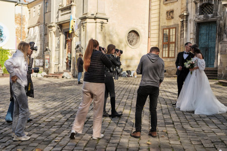 Lviv, Ukraine - October 28, 2022: Wedding Photography Masterclass. Young Attractive Marriage Couple Posing In The Old Town. Photographers shoot the bride and groomのeditorial素材