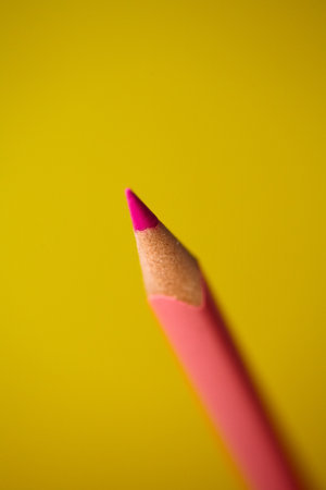 Pink coloring crayon pencil isolated on yellow background. Shallow depth of fieldの写真素材