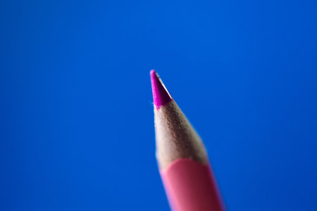 Pink coloring crayon pencil isolated on blue background. Shallow depth of fieldの写真素材