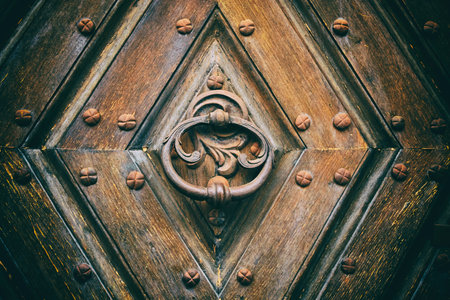 Antique round iron handle on an old Wooden door. Fragment of a brown ancient door.の写真素材