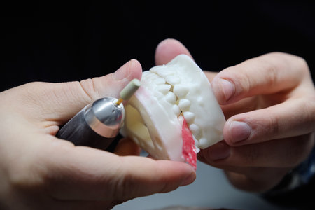 Dental technician using a drill to adjust and polish a large jaw model. This close-up shot...