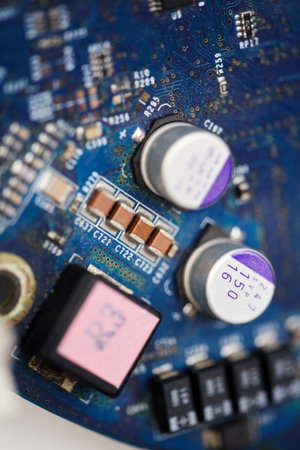 Vertical macro shot of blue circuit board with capacitors and microchips. Detailed electronic...