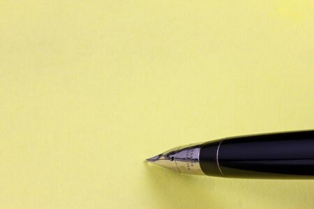 Fountain pen on a yellow post-it with copy spaceの写真素材