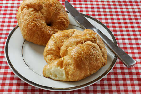A pair of croissants on a plate with a knifeの写真素材