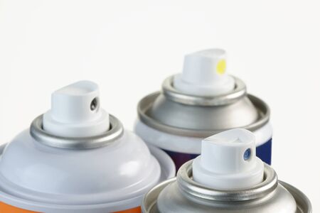 Close- up of the top of an aerosol can showing the spray nozzle.Out of focus cans in the background....