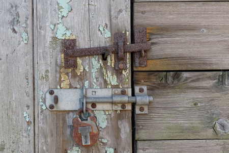 An old latch and padlock on a distressed door