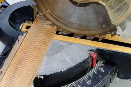 Industrial circular saw cutting a plank of wood in close up