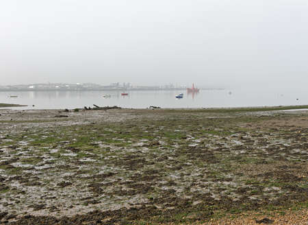 A riverside port in the mist with mudflats and moored yachtsの写真素材