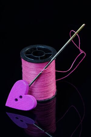 Heart shaped button with needle and thread symbolising love and togethernessの写真素材