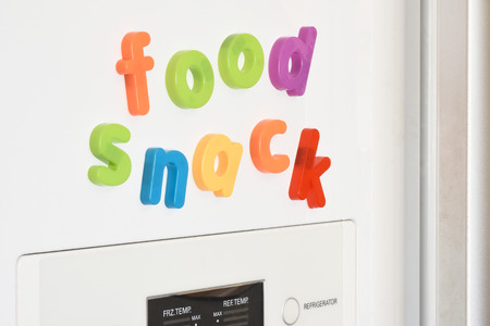 The words 'Food & Snack' spelled out in fridge magnets on the door of a fridge.の写真素材