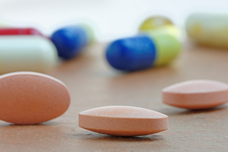 Close up of statin tablet or generic pill with out of focus tablets in backgroundの写真素材