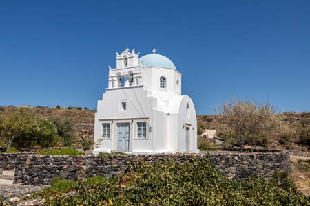 White church with blue dome and bell in Santoriniの写真素材
