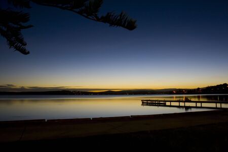 Peaceful long exposure overlooking calm water and a pier with children and bicycles.の写真素材