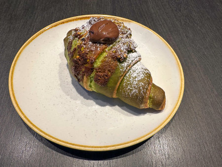 Chocolate croissant on a white plate with a dark backgroundの写真素材