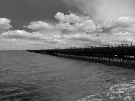 A Black and White image of a pier stretching into the seaの写真素材