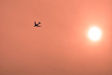 A jet plane flies into the orange sunset