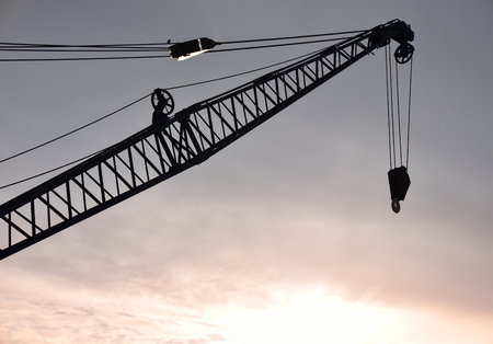 The arm and hook of a crane backlit by the Cardiff sunset