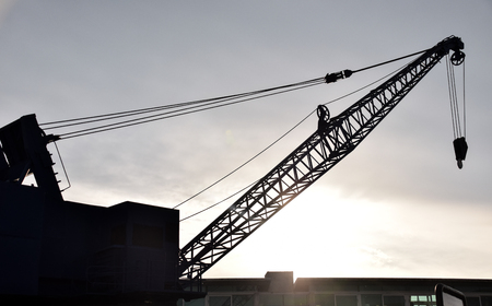A silhouette of an industrial crane at sunsetの写真素材