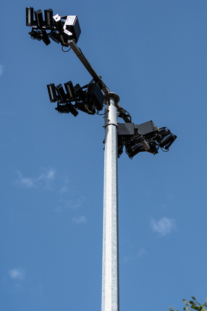A tall post toped by floodlights near a sports fieldの写真素材
