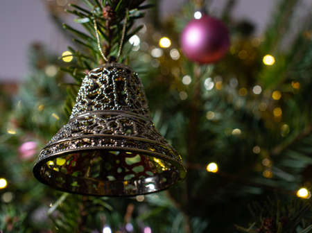 A Festive bell decoration hanging on a Christmas Tree