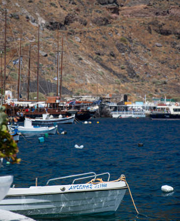 Ormos Korfou, Greece - July 16 2019:   A small boat called Antanhe  tied up to the dock at the scenic Santorini harbour of Ormos Korfouのeditorial素材