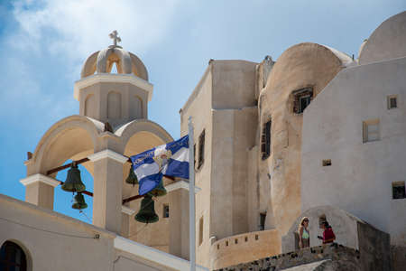 Emporio, Greece - July 14 2019:   The flag of Saint Spyridon flys in front of a church bell tower in the ecntre of Emporioのeditorial素材