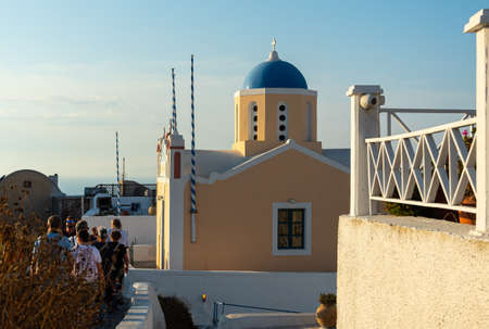 Oia, Greece - July 16 2019:   Tourists walk past an unusually coloured Greek orthodox church in the town centreのeditorial素材