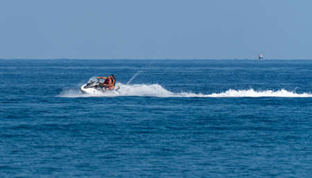 Perissa, Greece - July 13 2019:   A couple ride a jet ski across the waters of the Aegean Sea off the beach of Perissaのeditorial素材