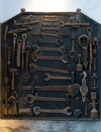 A wall mounted selection of old spanners, wrenches and other tools.