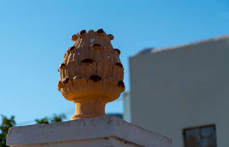 A decorative stone shape atop a gate post in Perissa