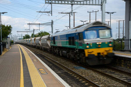 Thatcham, United Kingdom - June 09 2020:  A freight train pulled by a diesel locomotive speeding therough Thatcham Railway stationのeditorial素材