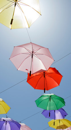 Brightly coloured umbrellas suspended from wiresの写真素材