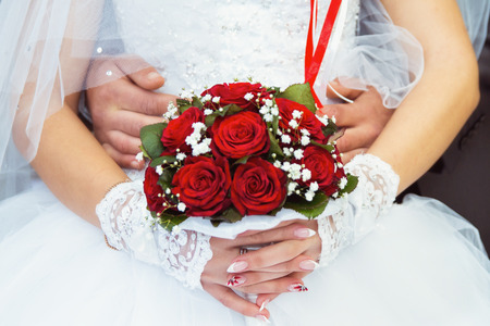 bride and groom gives bouquet of red rosesの写真素材