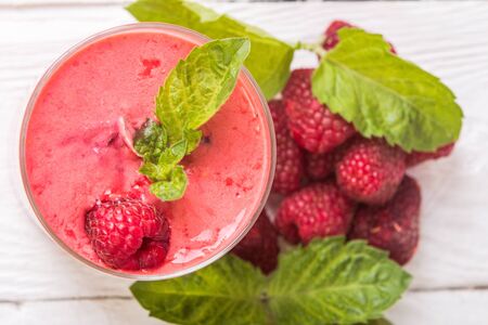 Smoothie in a glass and fresh raspberries