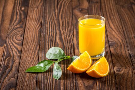 oranges and a glass of fresh juice on a wooden tableの写真素材