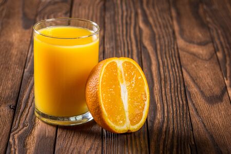 oranges and a glass of fresh juice on a wooden tableの写真素材