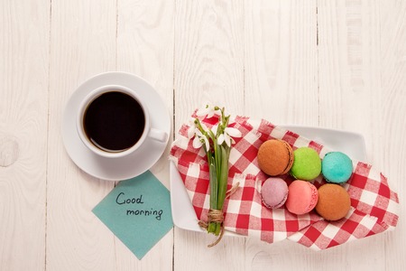 Beautiful delicious almond on a plate with snowdrops and a cup of coffee on a wooden tableの写真素材