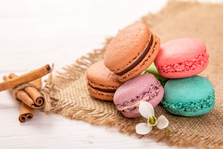 Colorful macaroons with cinnamon sticks on an old wooden tableの写真素材