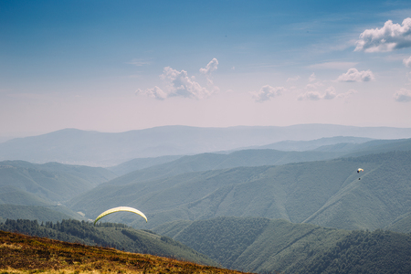 paraglider flies. paraglider over the tops of the mountains in summer sunny day.の写真素材