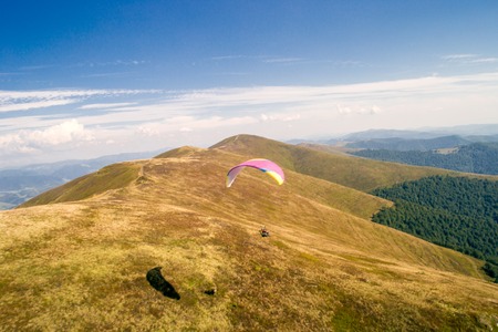 paraglider flies. paraglider over the tops of the mountains in summer sunny day.の写真素材