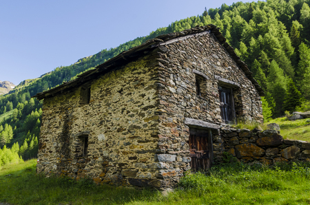 Stone shepherd s house in a peasant village in alpine meadows surrounded by mountains  Northern Italyのeditorial素材