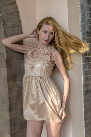 Beautiful blond girl walking in the park in a creamy dressの写真素材