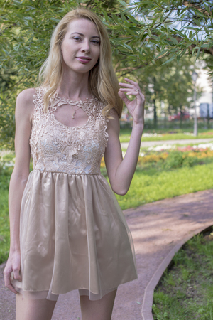 Beautiful blond girl walking in the park in a creamy dressの写真素材