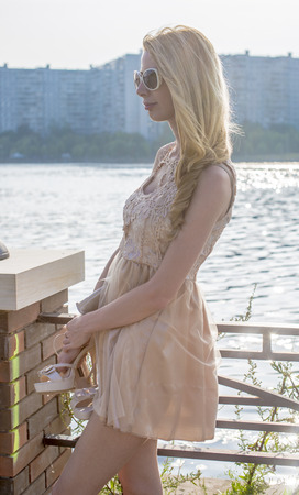 Beautiful blond girl walking in the park in a creamy dressの写真素材