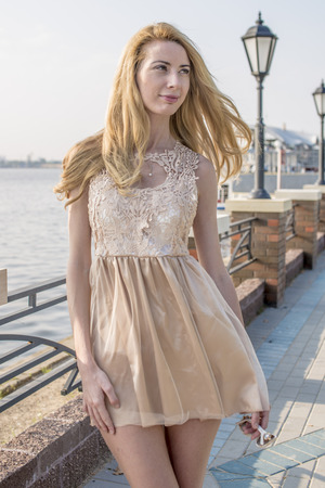 Beautiful blond girl walking in the park in a creamy dressの写真素材