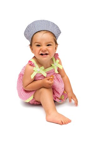 Cute little girl, naughty but cheerful, sitting on white, isolated background.の写真素材