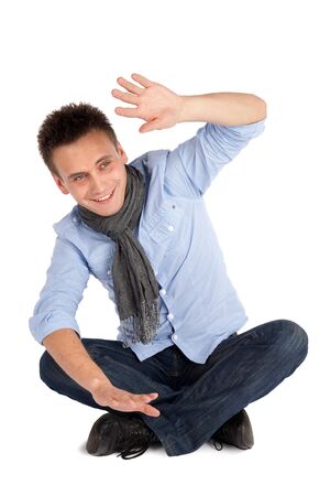 Cheerful smiling casual man sitting on the ground with legs crossed, isolated over white backgroundの写真素材