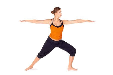 Fit attractive young woman practicing yoga exercise called Warrior Pose 2, sanskrit name: Virabhadrasana 2, this posture strengthens and stretches legs, ankles, groins, chest, lungs and shouldersの写真素材